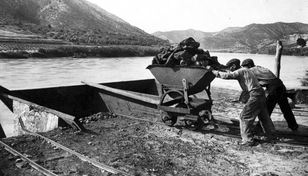 Unos trabajadores cargan un barco de carb&oacute;n en el r&iacute;o Ebro en los alrededores de Mequinenza a principios del siglo XX.