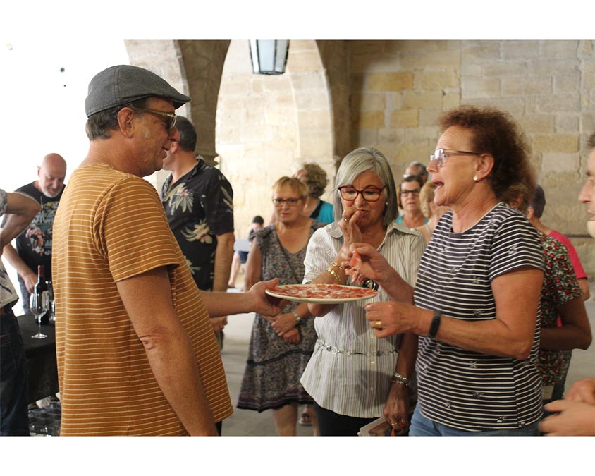 Diversas personas disfrutando de jamón al corte en la previa del Matarraña Intím del 26-07-2023